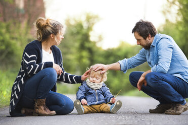 Parents stroking cute little boy on field path - HAPF02313