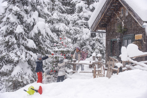 Austria, Altenmarkt-Zauchensee, family decorating Christmas tree at wooden house stock photo