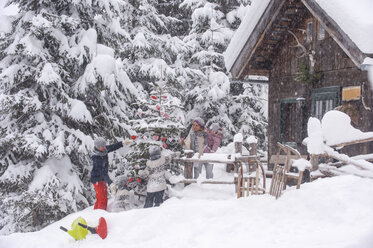 Österreich, Altenmarkt-Zauchensee, Familie schmückt Weihnachtsbaum in Holzhaus - HHF05491