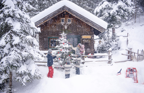 Austria, Altenmarkt-Zauchensee, family decorating Christmas tree at wooden house stock photo