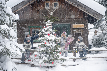 Austria, Altenmarkt-Zauchensee, family decorating Christmas tree at wooden house - HHF05496