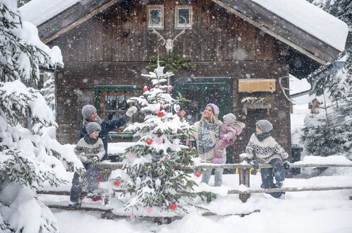 Österreich, Altenmarkt-Zauchensee, Familie schmückt Weihnachtsbaum in Holzhaus - HHF05496