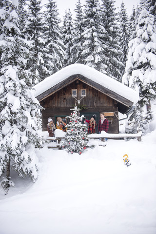 Austria, Altenmarkt-Zauchensee, friends decorating Christmas tree at wooden house stock photo