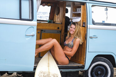 Portrait of happy young woman with surfboard in van - SIPF01801