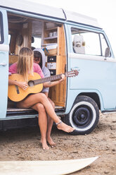Junges Paar mit Gitarre und Surfbrett im Van am Strand - SIPF01813
