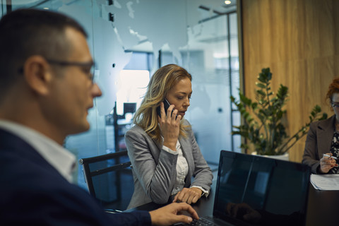 Businesswoman on cell phone during a meeting stock photo