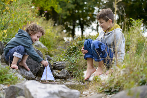 Zwei Jungen spielen mit einem Spielzeugboot in einem Bach - LBF01693