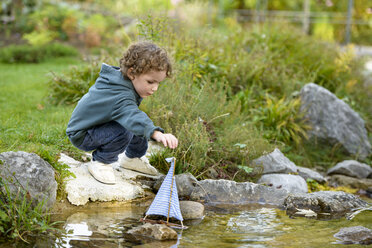 Toddler playing with a toy boat in a brook - LBF01694