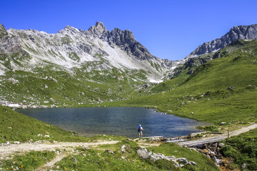 Austria, Vorarlberg, Hiker standing at mountain lake - PUF00864
