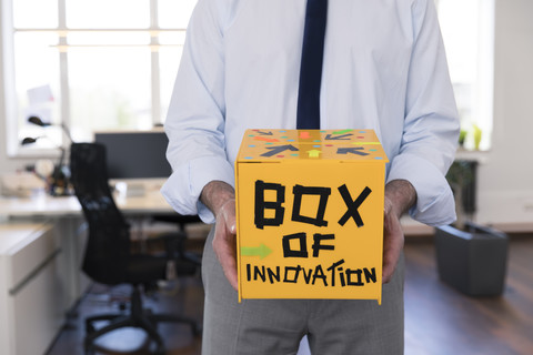 Geschäftsmann sammelt innovative Vorschläge in gelber Box, lizenzfreies Stockfoto