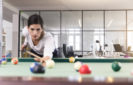 Entschlossene Geschäftsfrau spielt Pool-Billard in einem modernen Büro - FKF02644