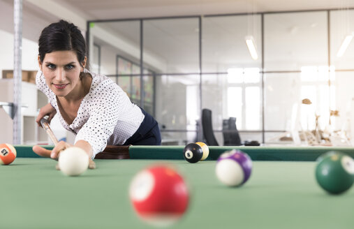 Entschlossene Geschäftsfrau spielt Pool-Billard in einem modernen Büro - FKF02645