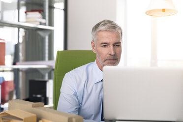 Geschäftsmann, der im Büro arbeitet und einen Laptop benutzt - FKF02665