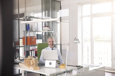 Geschäftsmann bei der Arbeit in seinem Büro, mit aptop - FKF02668