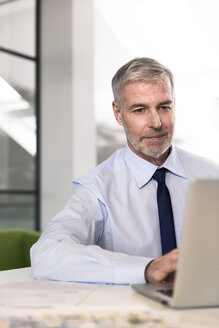 Geschäftsmann, der im Büro arbeitet und einen Laptop benutzt - FKF02684