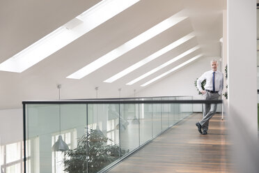 Gelassener Geschäftsmann im Büro stehend, lächelnd - FKF02687