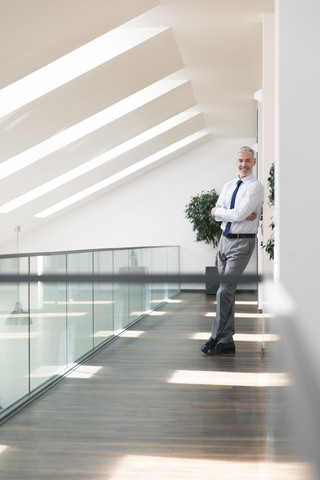 Gelassener Geschäftsmann im Büro stehend, lächelnd, lizenzfreies Stockfoto