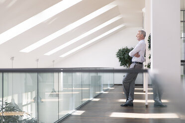 Businessman leaning against wall, smiling relaxed - FKF02689