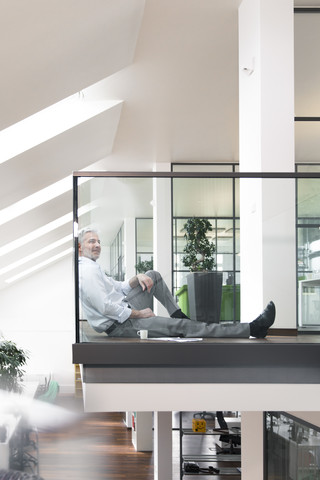 Businessman sitting on floor in the office, taking a break stock photo