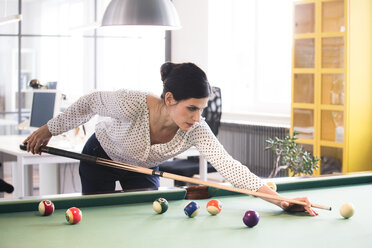 Entschlossene Geschäftsfrau spielt Pool-Billard in einem modernen Büro - FKF02712