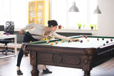 Entschlossene Geschäftsfrau spielt Pool-Billard in einem modernen Büro - FKF02713