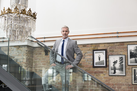 Älterer Geschäftsmann in modernem Büro auf einer Treppe stehend, lizenzfreies Stockfoto