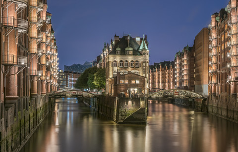 Deutschland, Hamburg, Speicherstadt, beleuchtete Altbauten mit Elbphilharmonie im Hintergrund, lizenzfreies Stockfoto