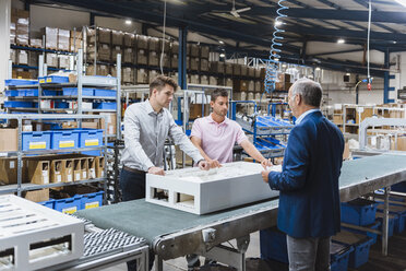 Business people standing on shop floor, discussing product improvement - DIGF02967