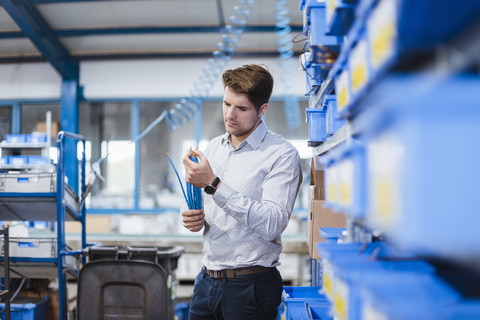 Geschäftsmann steht in der Werkstatt und testet Produkte, lizenzfreies Stockfoto