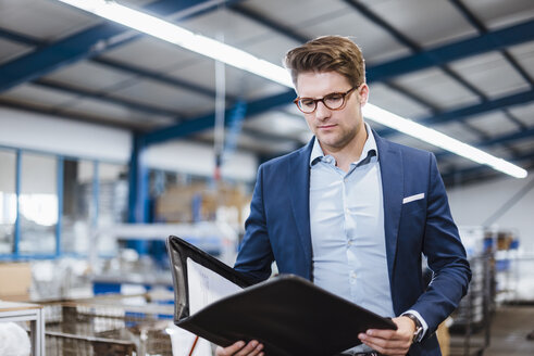 Porträt eines jungen Managers in der Werkstatt, der eine Akte hält - DIGF02984