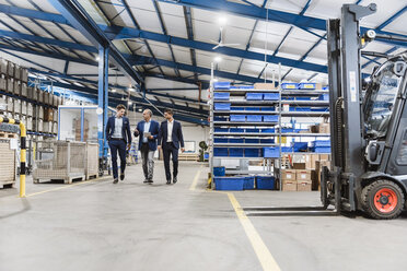 Three businessmen walking through shop floor, discussing decisions - DIGF02990