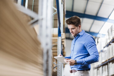 Young man working in warehouse, using digital tablet - DIGF03001