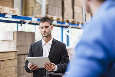 Employees having a meeting in storehouse, using digital tablet - DIGF03009