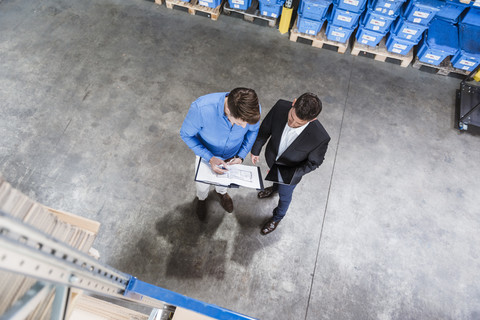 Zwei Geschäftsleute bei einem Treffen in einem Firmenlager, lizenzfreies Stockfoto