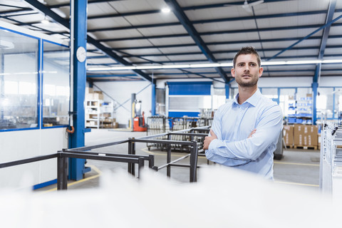 Angestellter, der mit verschränkten Armen in der Werkstatt steht, Porträt, lizenzfreies Stockfoto