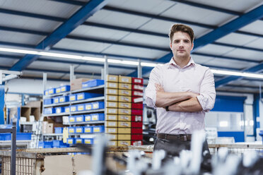 Employee standing in shop floor with arms crossed, portrait - DIGF03023