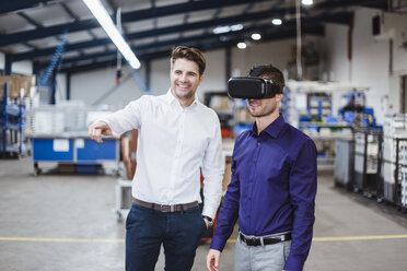 Two employees having a meeting, one wearing VR goggles - DIGF03043