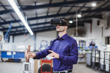 Company employee wearing VR goggles in shop floor - DIGF03044