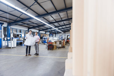 Two businessman standing in shop floor, discussing plans - DIGF03052