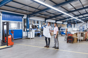 Two businessman standing in shop floor, discussing plans - DIGF03053