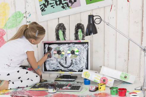Mädchen malt Kaninchenohren auf PC im Büro - DRF01728
