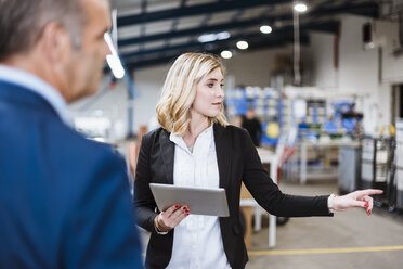 Businesswoman talking to business founder, holding digital tablet - DIGF03064