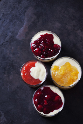Rotes und gelbes Fruchtkompott mit Vanillesoße in Gläsern geschichtet, lizenzfreies Stockfoto
