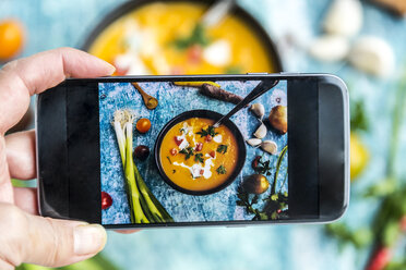 Frau fotografiert mit einem Smartphone eine Süßkartoffelsuppe - SARF03398