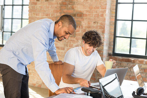 Zwei junge Geschäftsleute arbeiten zusammen in einem Co-Working Space und benutzen Laptops - SPCF00180