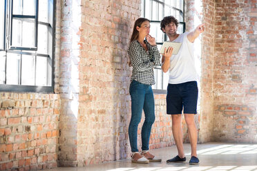 Two young entrepreneurs viewing loft, reading rental contract on digital tablet - SPCF00185