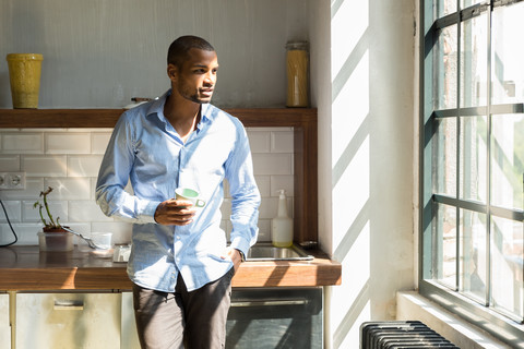 Junger Unternehmer steht in der Firmenküche und trinkt Kaffee, lizenzfreies Stockfoto