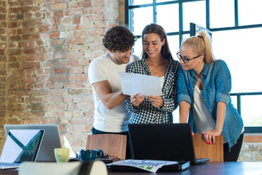 Junge Geschäftsleute, die im Büro sitzen und den Geschäftsplan für ihr Start-up-Unternehmen lesen - SPCF00218