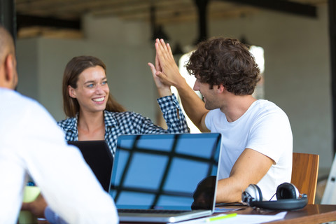 Young cooleagues working together in start up company, giving high five stock photo