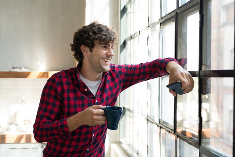 Young entrepreneur standing in company kitchen, drinking coffee stock photo